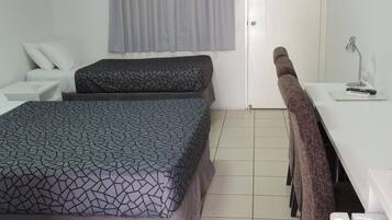 Una habitación de hotel con cama, escritorio, silla y zona de ducha.