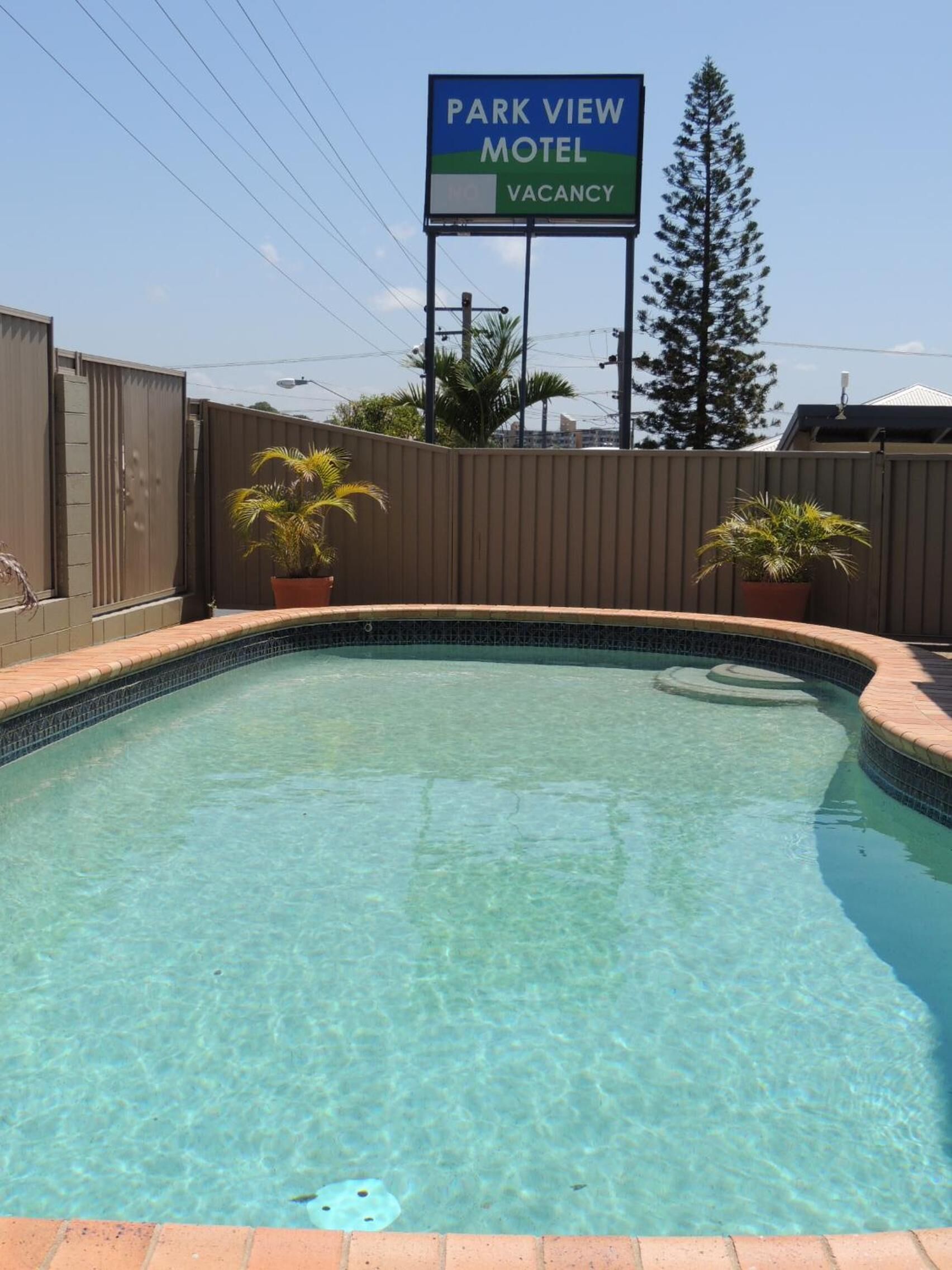 A clear swimming pool with a sign for Park View Motel indicating vacancy.