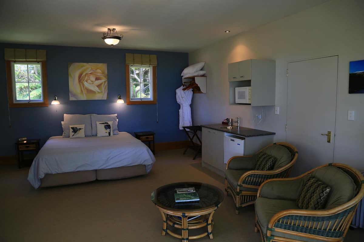 A bedroom with a bed, bedside tables, a desk, a chair, a small table, and a window.