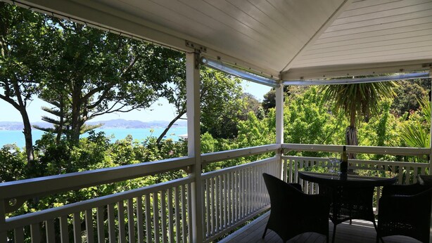 A covered outdoor area with a white railing, a table, and two chairs. - Villa Russell (Russell)