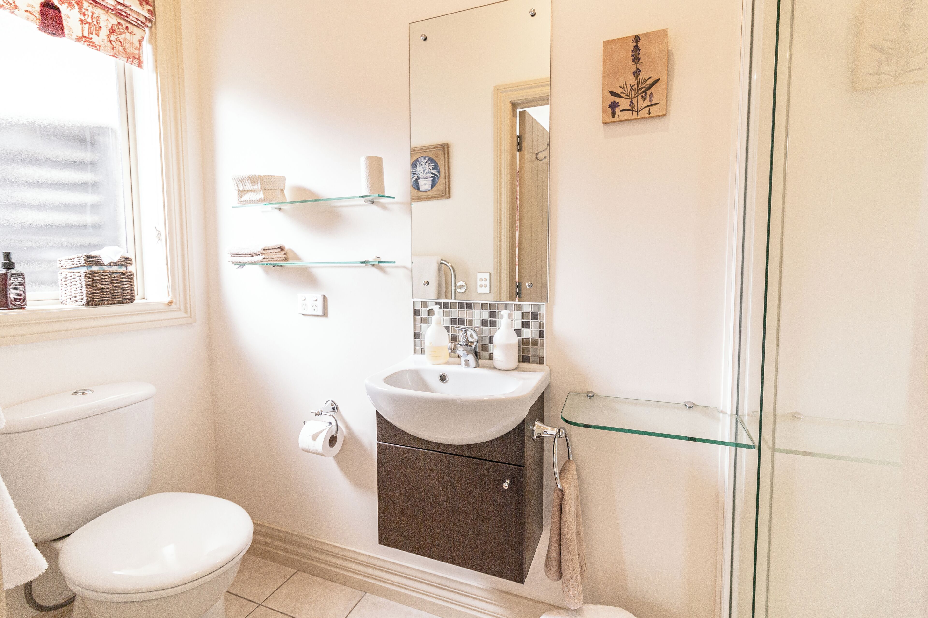 Un baño con inodoro, lavamanos y cabina de ducha de vidrio.