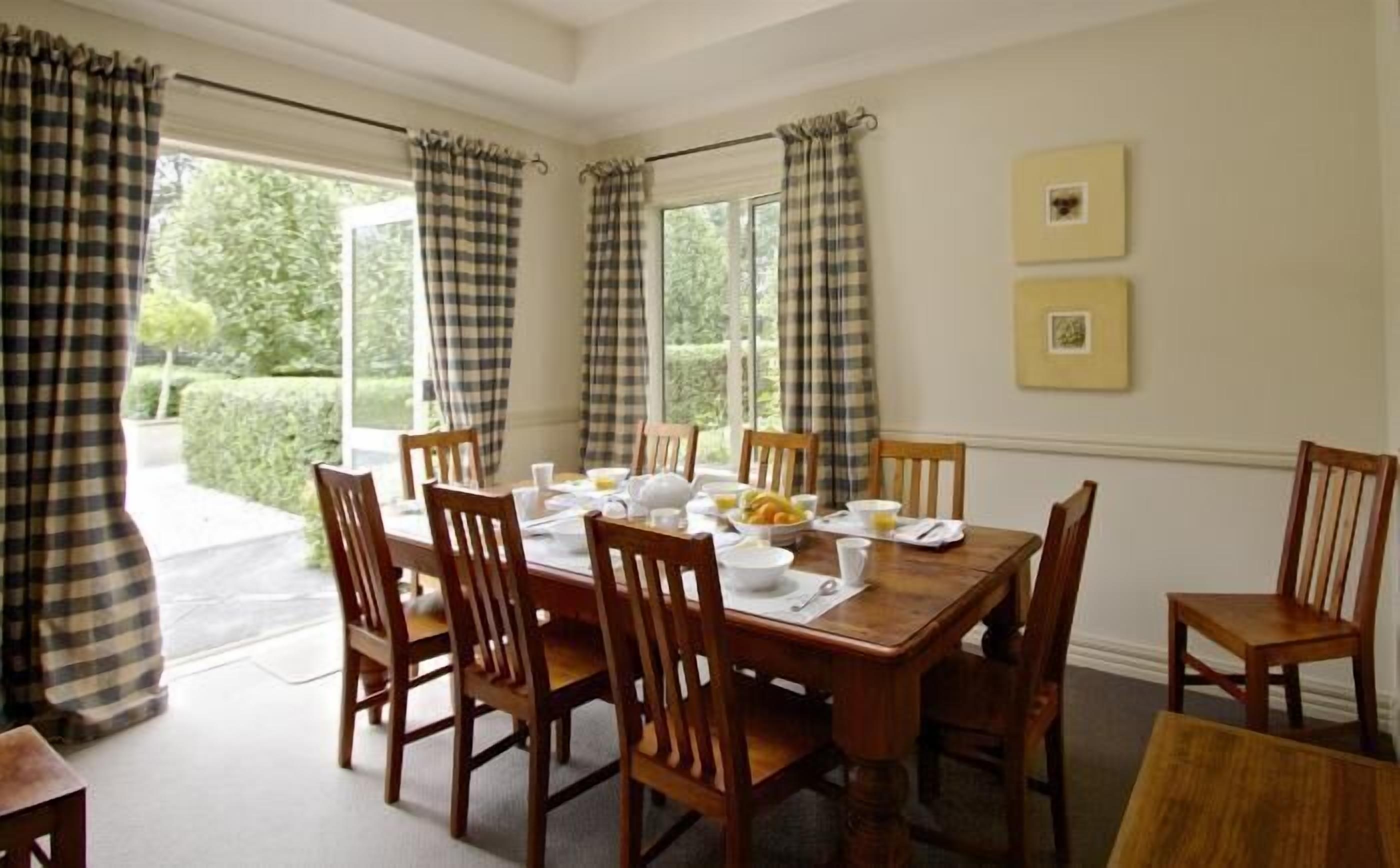 Comedor con una mesa de madera dispuesta para seis personas, rodeada por seis sillas de madera.