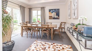 A dining area with a wooden table and chairs, a buffet station, and a large window with curtains. - Ruapehu Country Lodge (Ohakune)