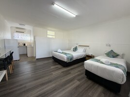 Habitación de hotel con dos camas, kitchenette, zona de comedor y baño.