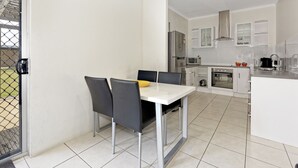 A modern kitchen with white cabinets, a stainless steel refrigerator, and a microwave.