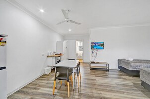 Una habitación moderna y luminosa con una mesa de comedor, sillas, una cama y un televisor.