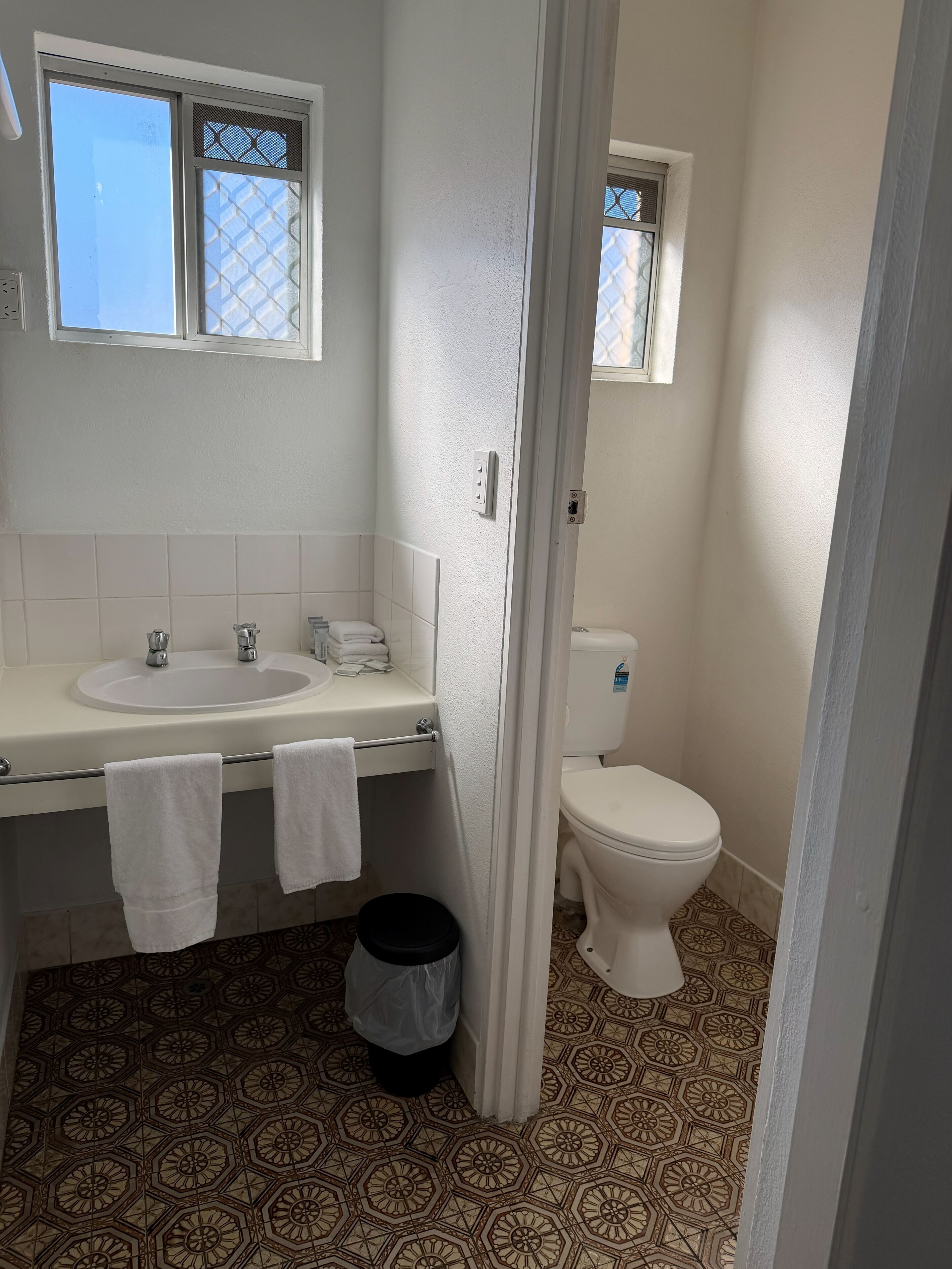 A bathroom with a sink, toilet, and patterned floor tiles.