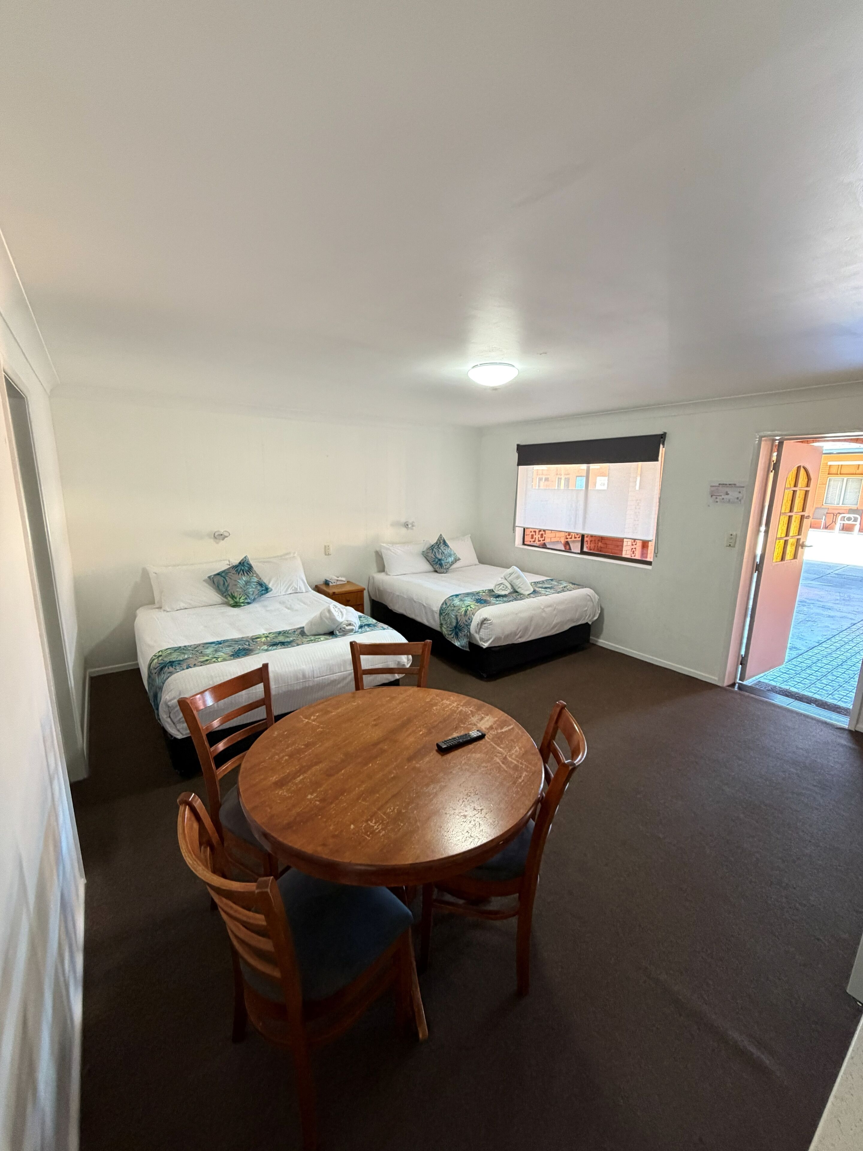 Une chambre d’hôtel avec deux lits, une table ronde en bois et des chaises.