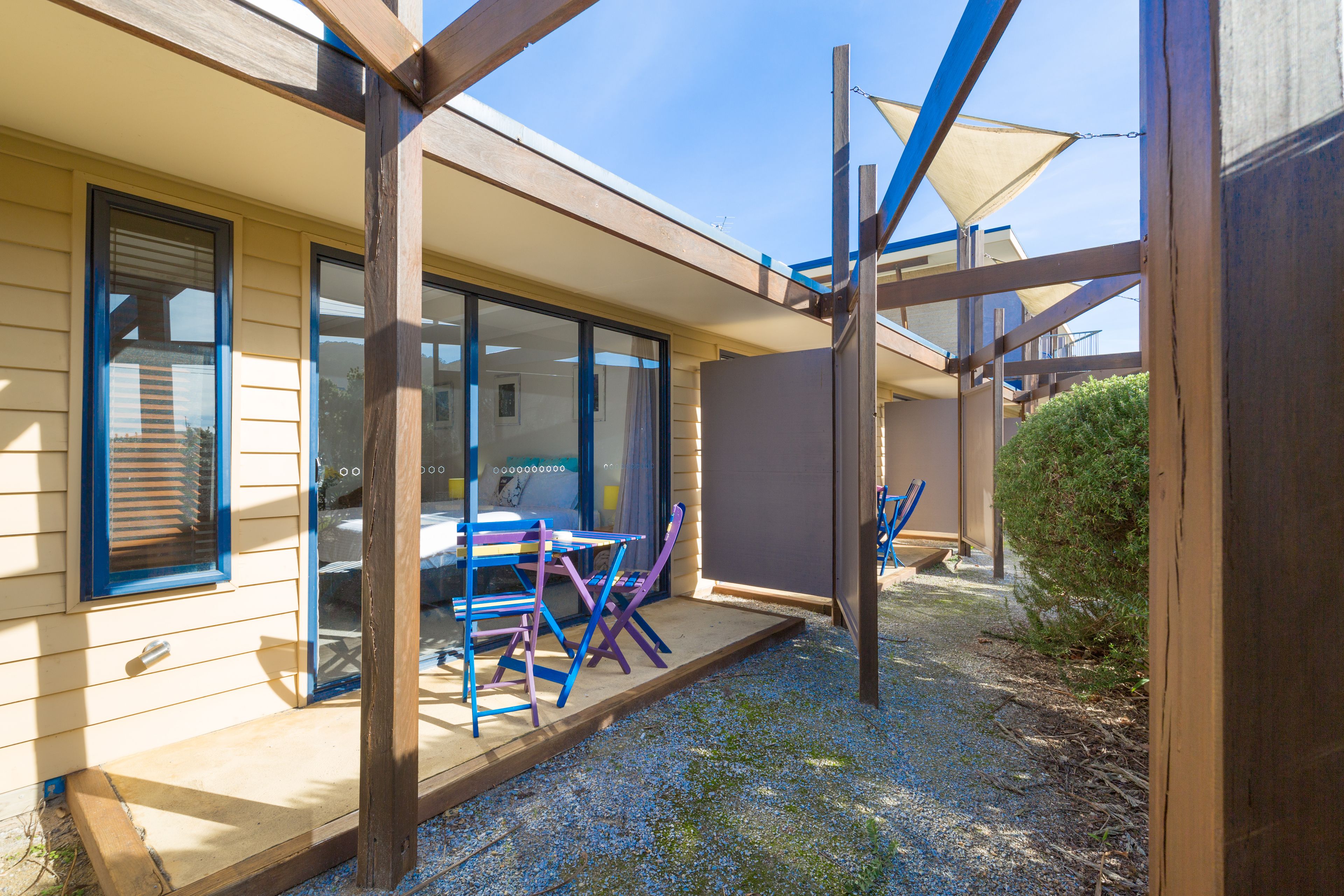 Un patio techado al aire libre con una mesa y sillas, una terraza de madera y vistas de la casa.