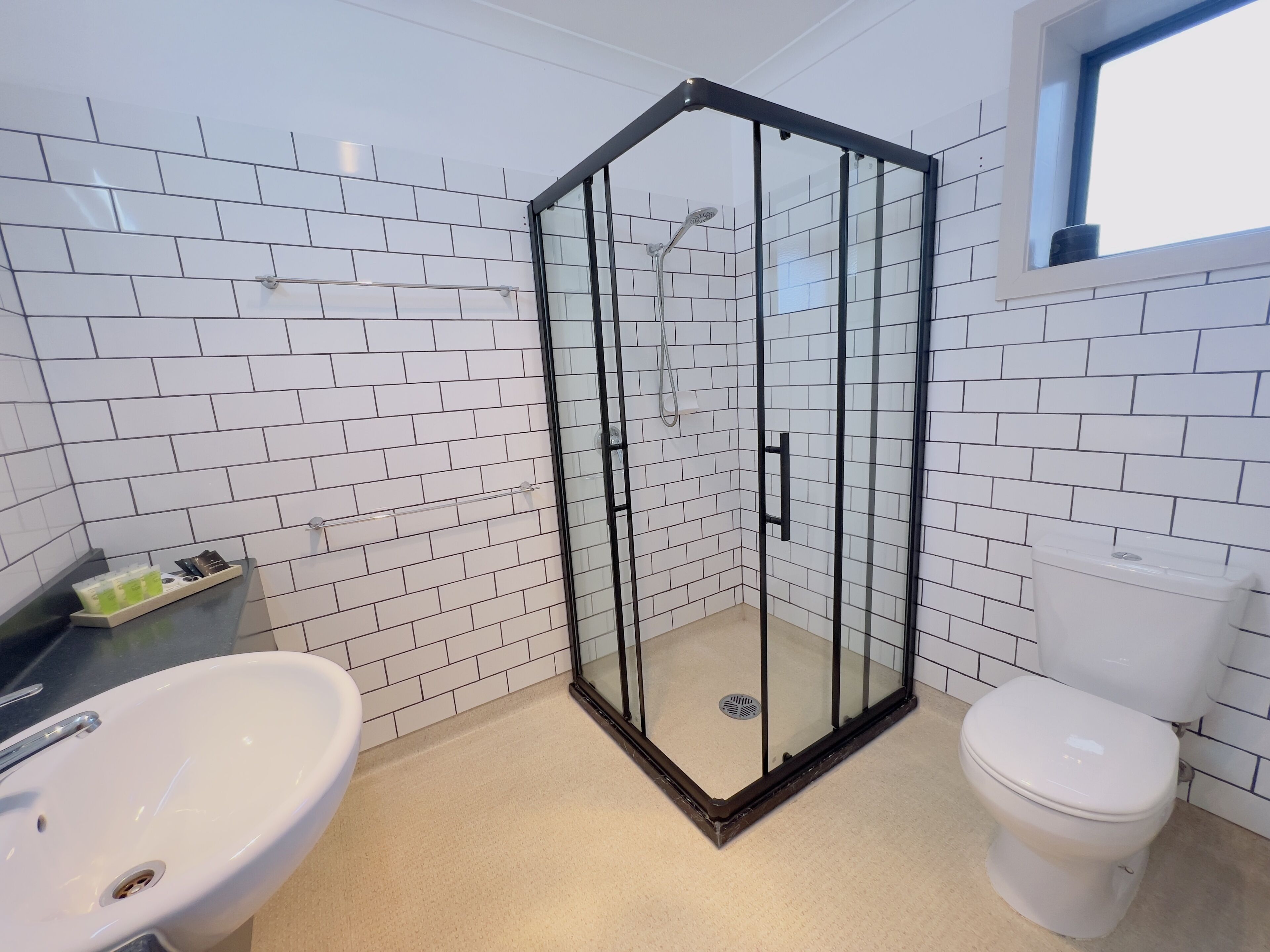 A bathroom with a glass-enclosed shower, a sink, and a toilet.