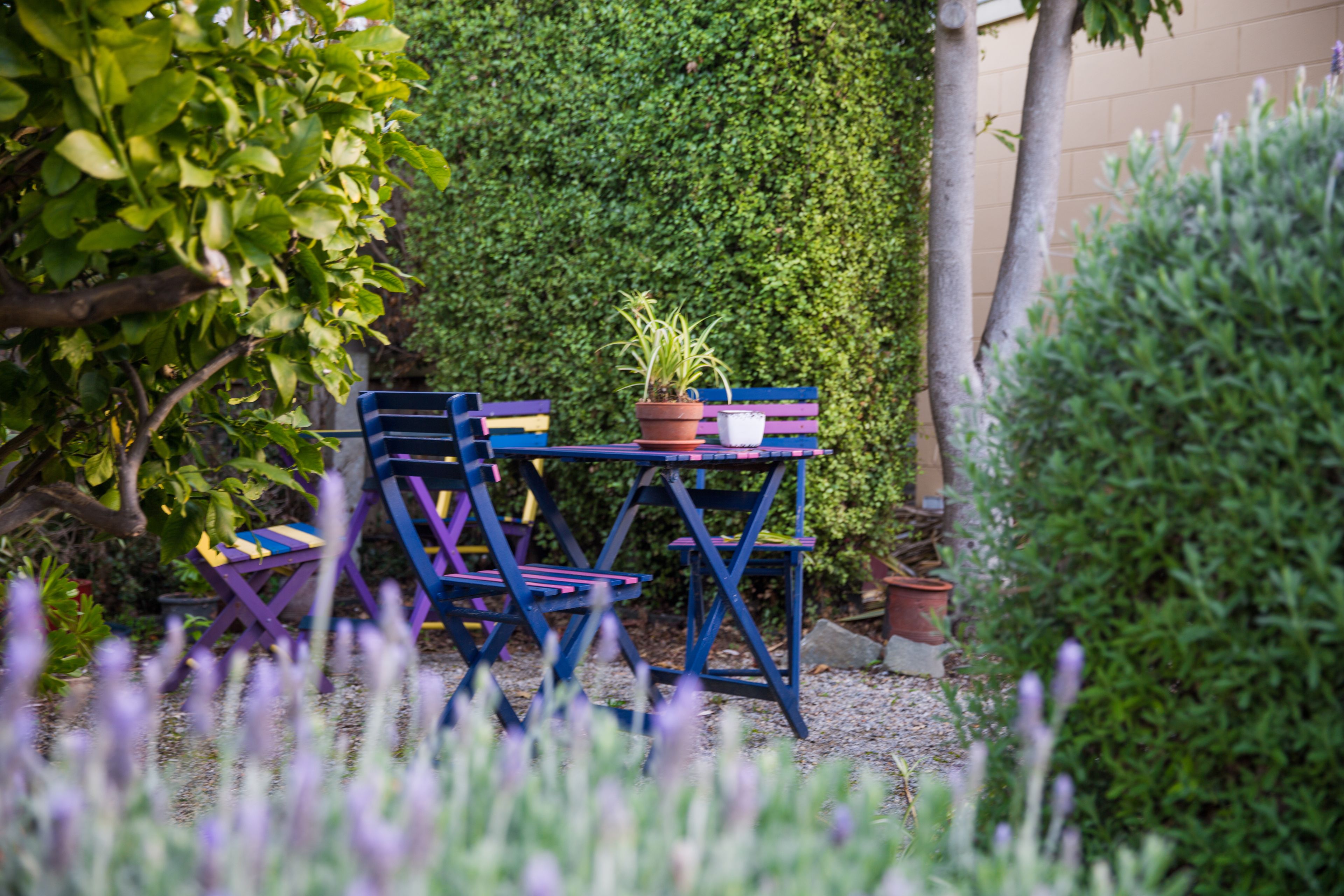 Een tuin met een tafel en stoelen, omgeven door groen en planten.