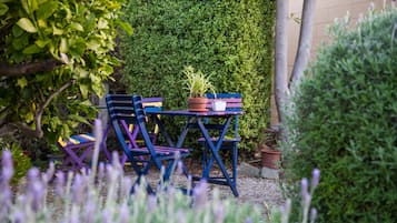 Een tuin met een tafel en stoelen, omgeven door groen en planten.