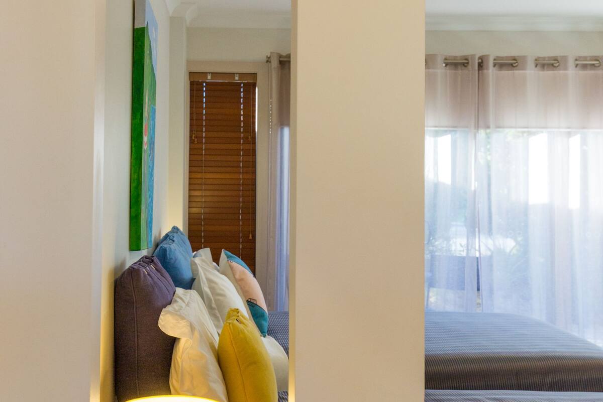 Habitació d'hotel amb un llit, una tauleta de nit amb una làmpada i una finestra amb cortines.