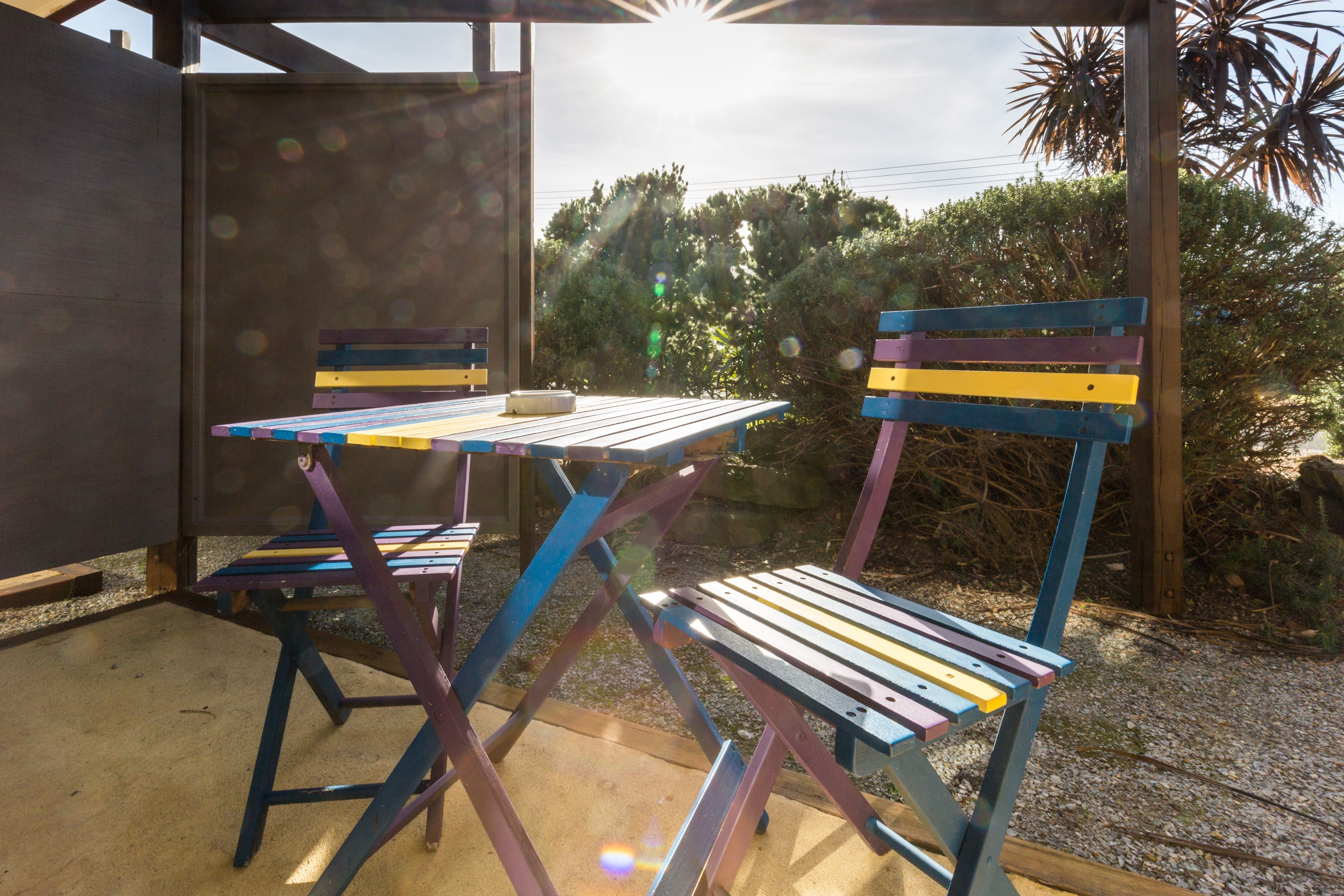 Un espace extérieur aménagé avec une table et des chaises, entouré de verdure et d’une structure en bois.