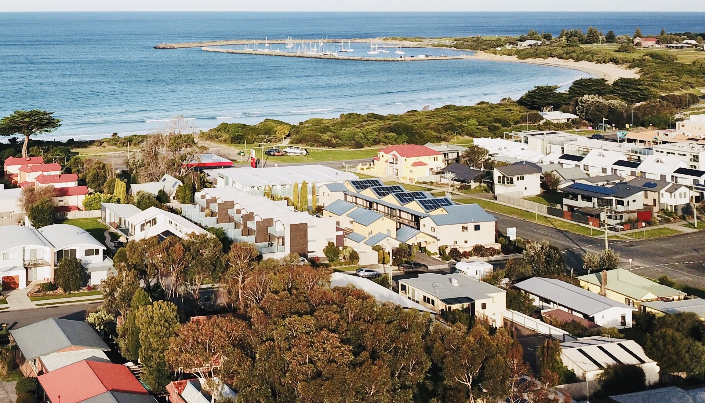 A coastal residential area with houses, a marina, and a beach.