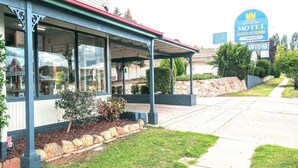 Un motel con un porche techado, un letrero y un césped cuidado.