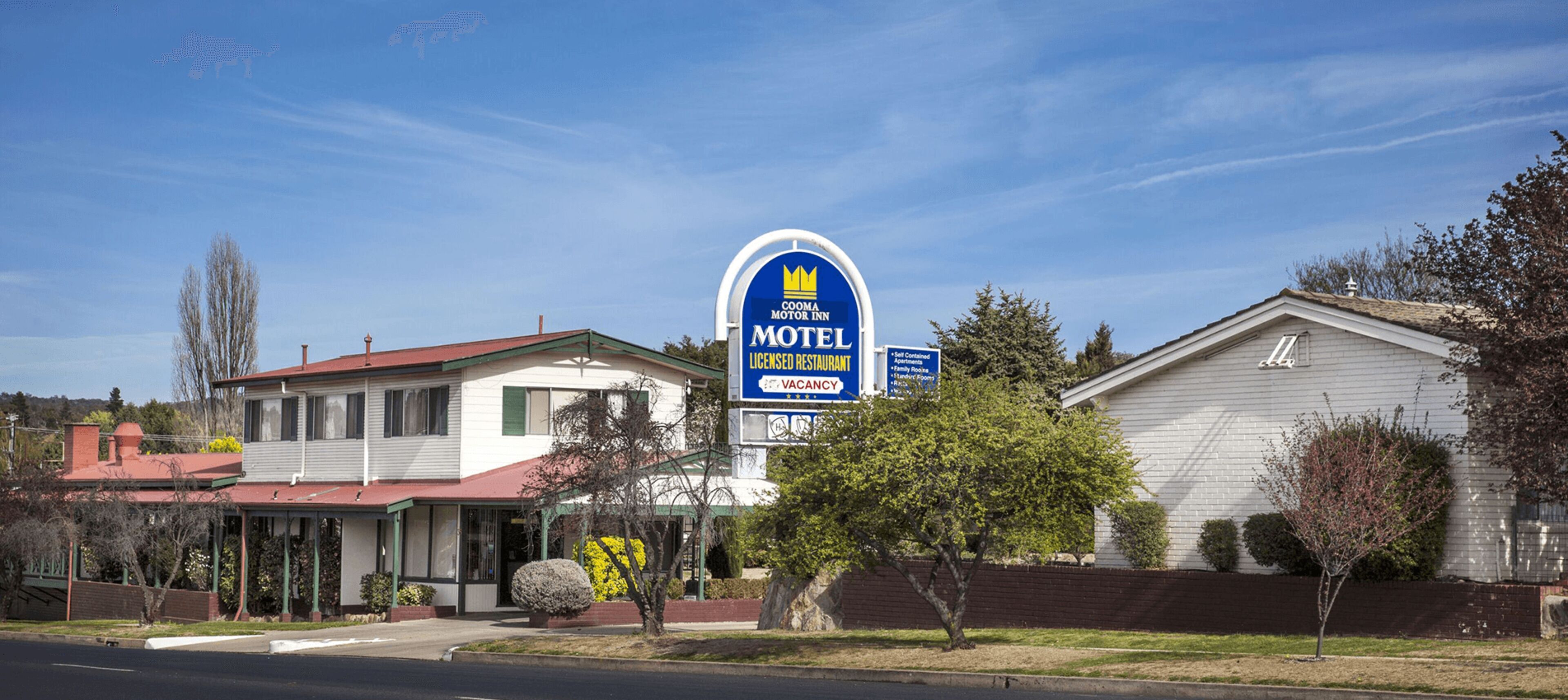 A motel with a red roof, a white exterior, and a blue sign indicating a licensed restaurant.