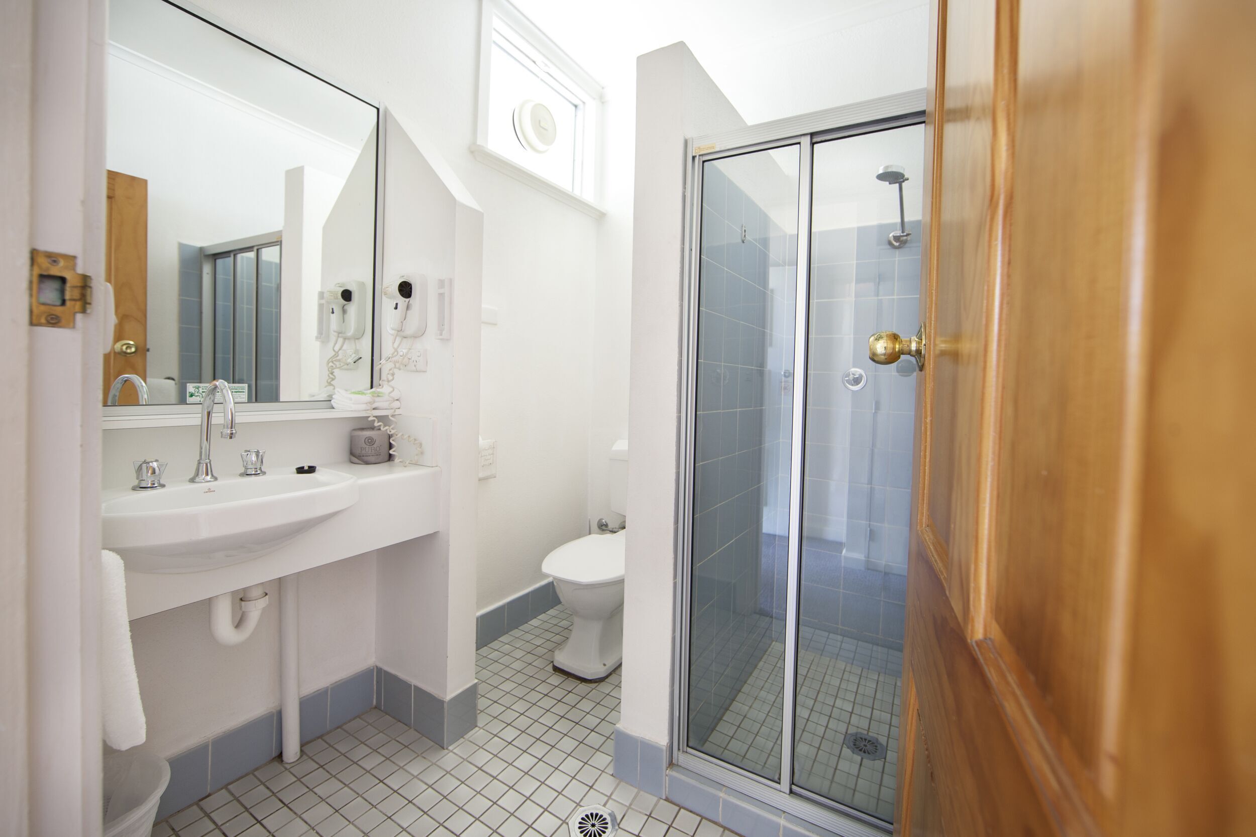 A bathroom with a sink, mirror, toilet, and a glass-enclosed shower.