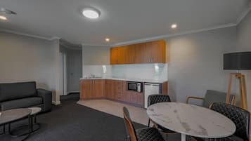 A compact living space with a kitchenette, a sofa, a dining table, and a lamp.