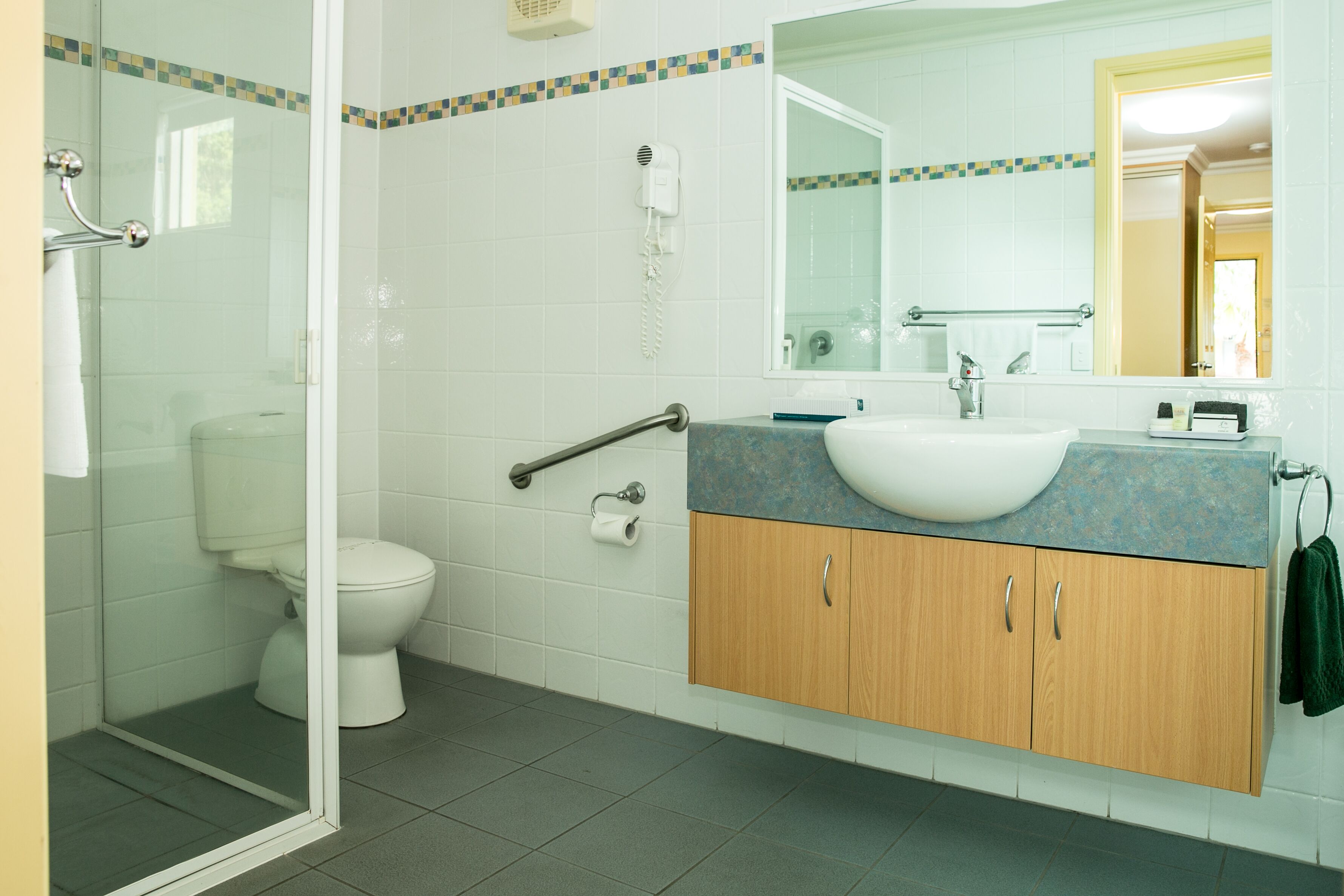 Une salle de bain avec une douche à parois de verre, des toilettes, un lavabo avec un miroir et un porte-serviettes.