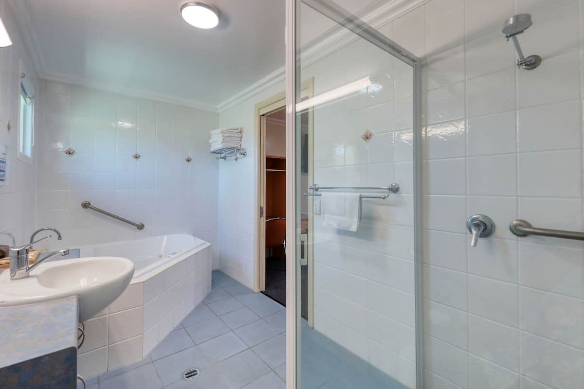 A modern bathroom with a glass shower enclosure, a bathtub, and a sink with a mirror.