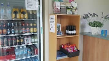 Un refrigerador lleno de bebidas variadas, una estantería con botellas de vino y una presentación de aperitivos.