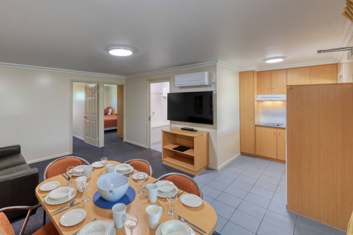A compact living space with a dining area, a sofa, a TV, and a kitchenette.