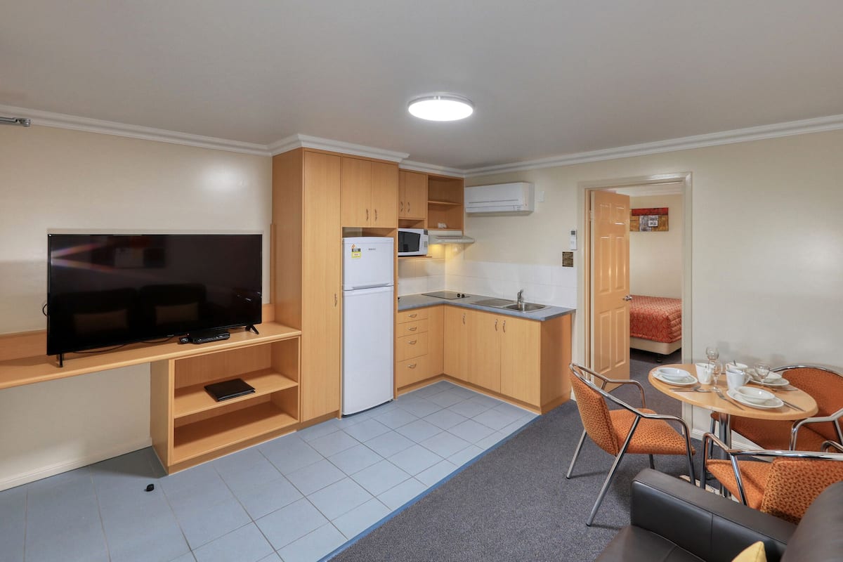 A compact kitchenette with a microwave, refrigerator, and a flat-screen TV.
