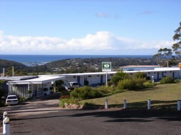 Un motel con vista al océano y colinas al fondo.