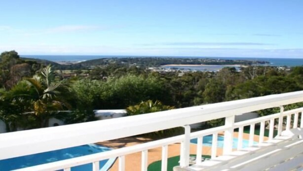 A poolside view with a clear view of the ocean and surrounding greenery. - Kingfisher Motel (Merimbula)