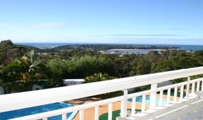 Blick auf einen Pool mit freiem Blick auf das Meer und die umliegende Vegetation.