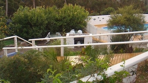 A pool area with a white fence, surrounded by lush greenery and trees. - Kingfisher Motel (Merimbula)