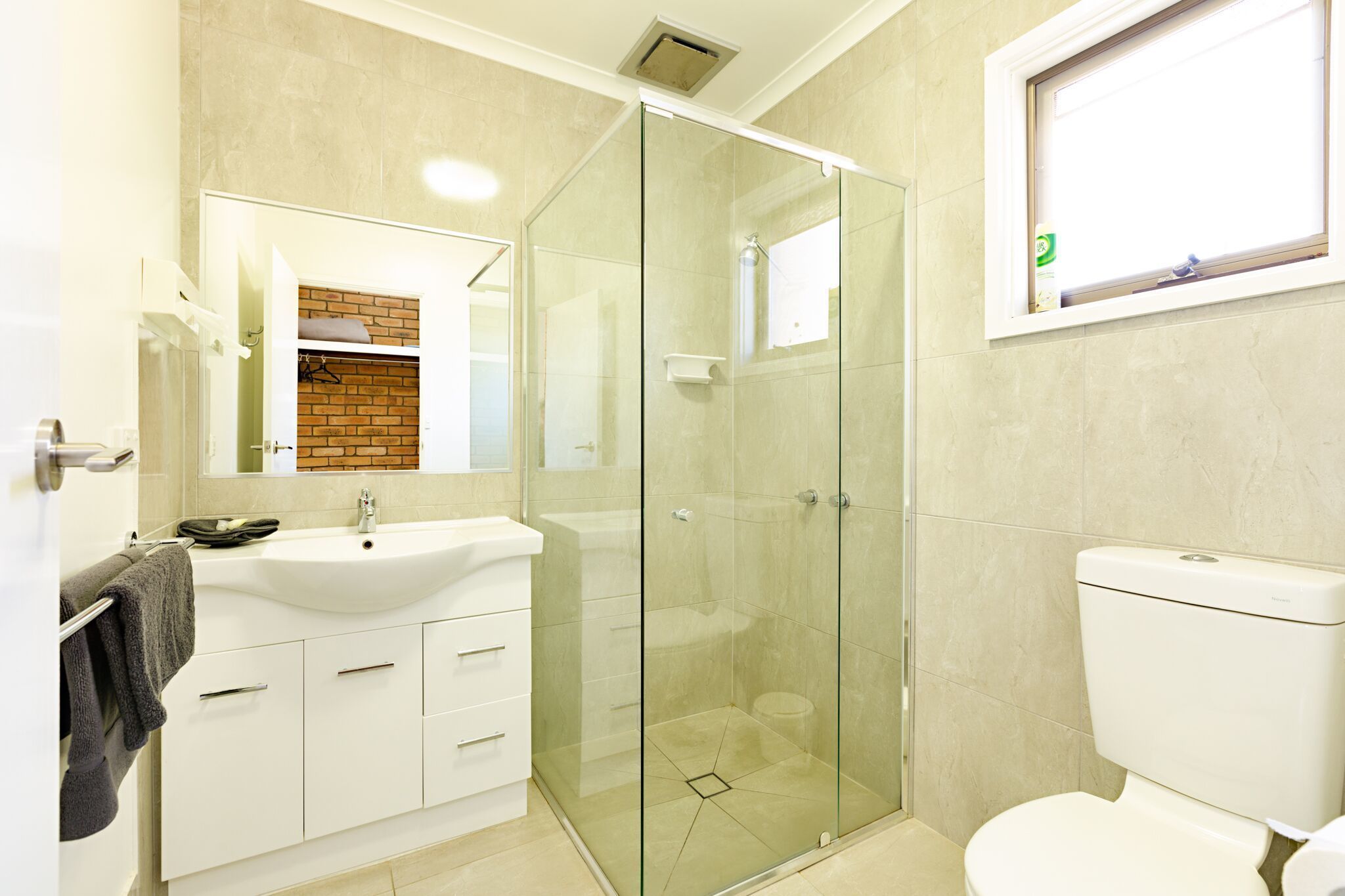 A bathroom with a glass-enclosed shower, a white sink, and a toilet.
