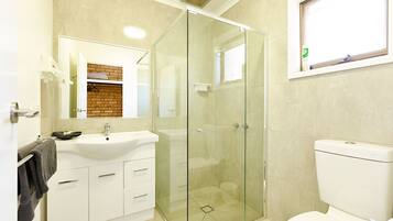 A bathroom with a glass-enclosed shower, a white sink, and a toilet.
