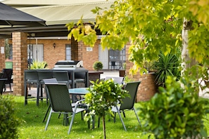 An outdoor seating area with brick walls, a covered patio, and a barbecue grill.