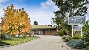 A Statesman Motor Inn with a gravel driveway, a brick building, and a signboard indicating corporate rates, group bookings, and a vacancy. - Statesman Motor Inn (Corowa)