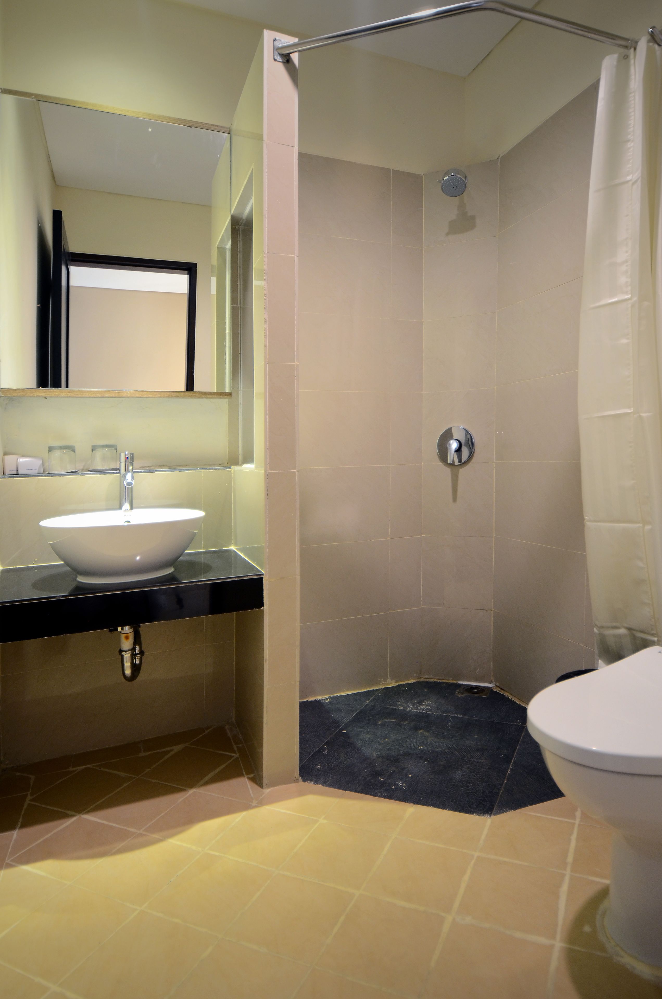 A bathroom with a sink, mirror, shower, and toilet.