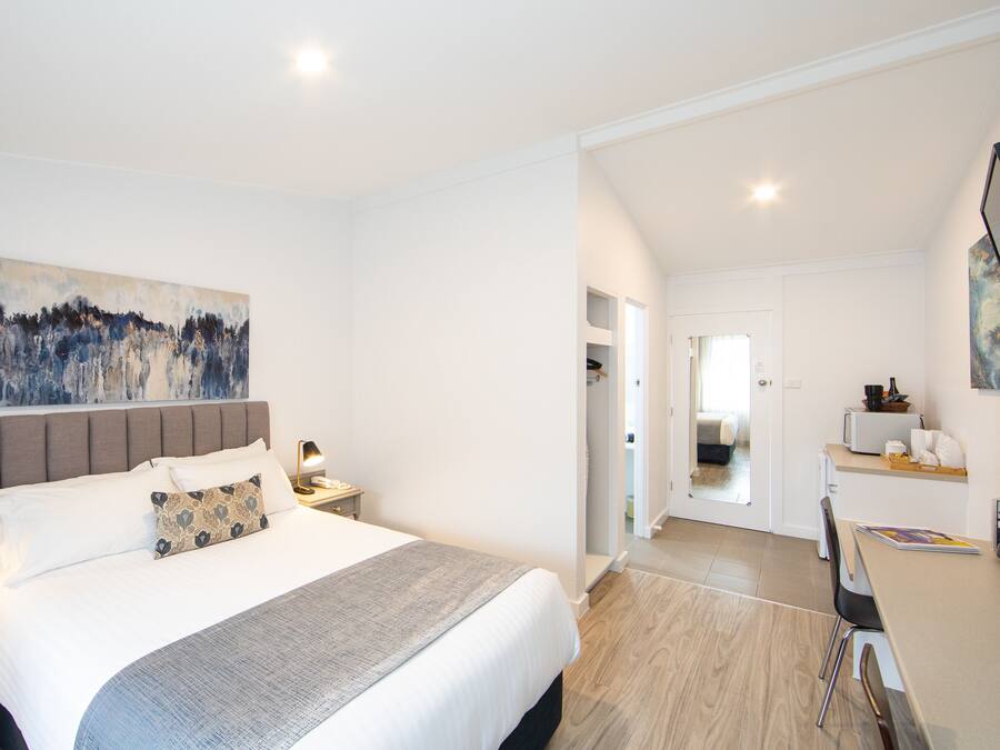 Ein modernes Schlafzimmer mit einem großen Bett, Nachttischen und einem Bild an der Wand.