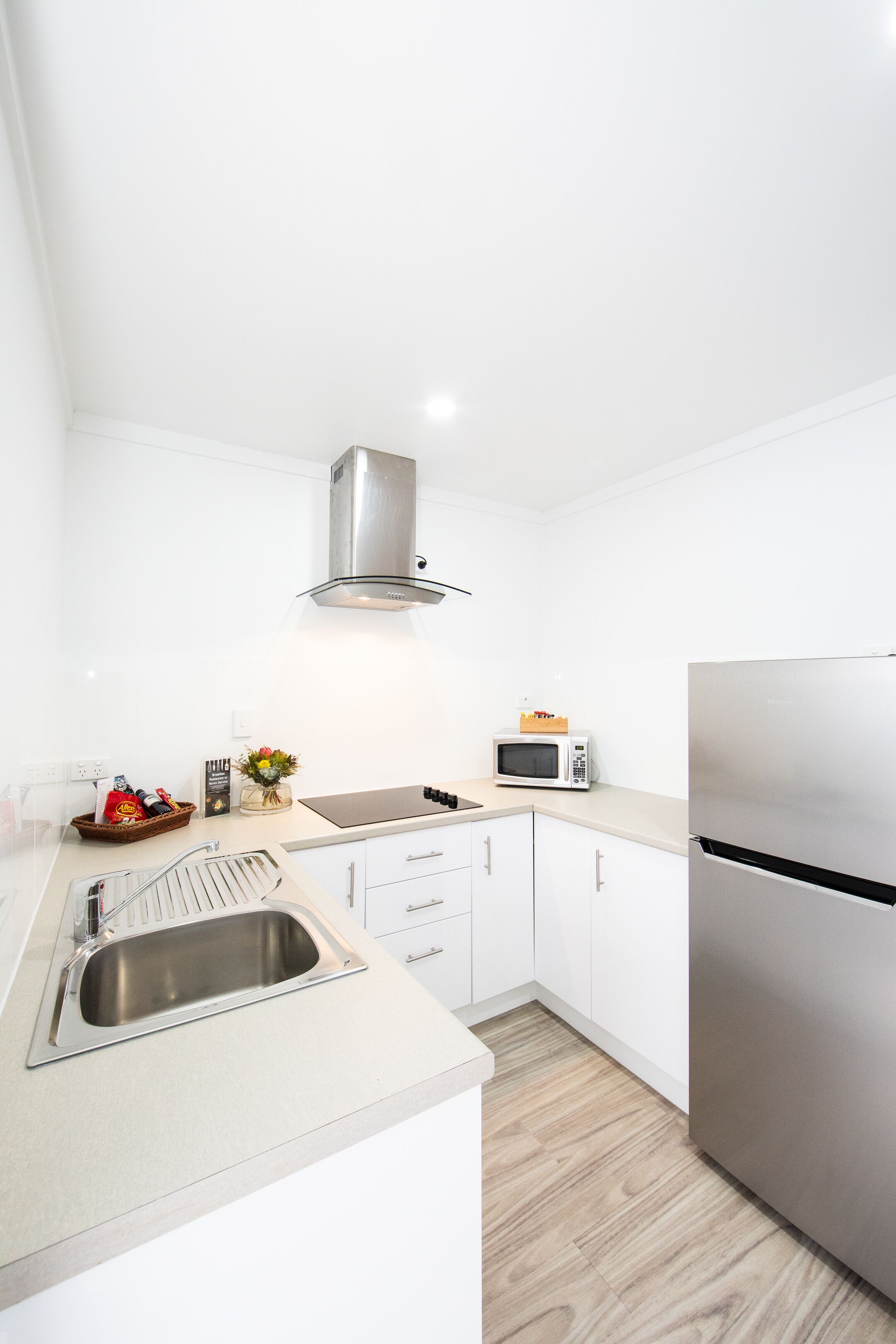 Una cocina moderna con gabinetes blancos, electrodomésticos de acero inoxidable y piso de madera.