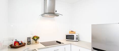Una cocina moderna con gabinetes blancos, electrodomésticos de acero inoxidable y piso de madera.