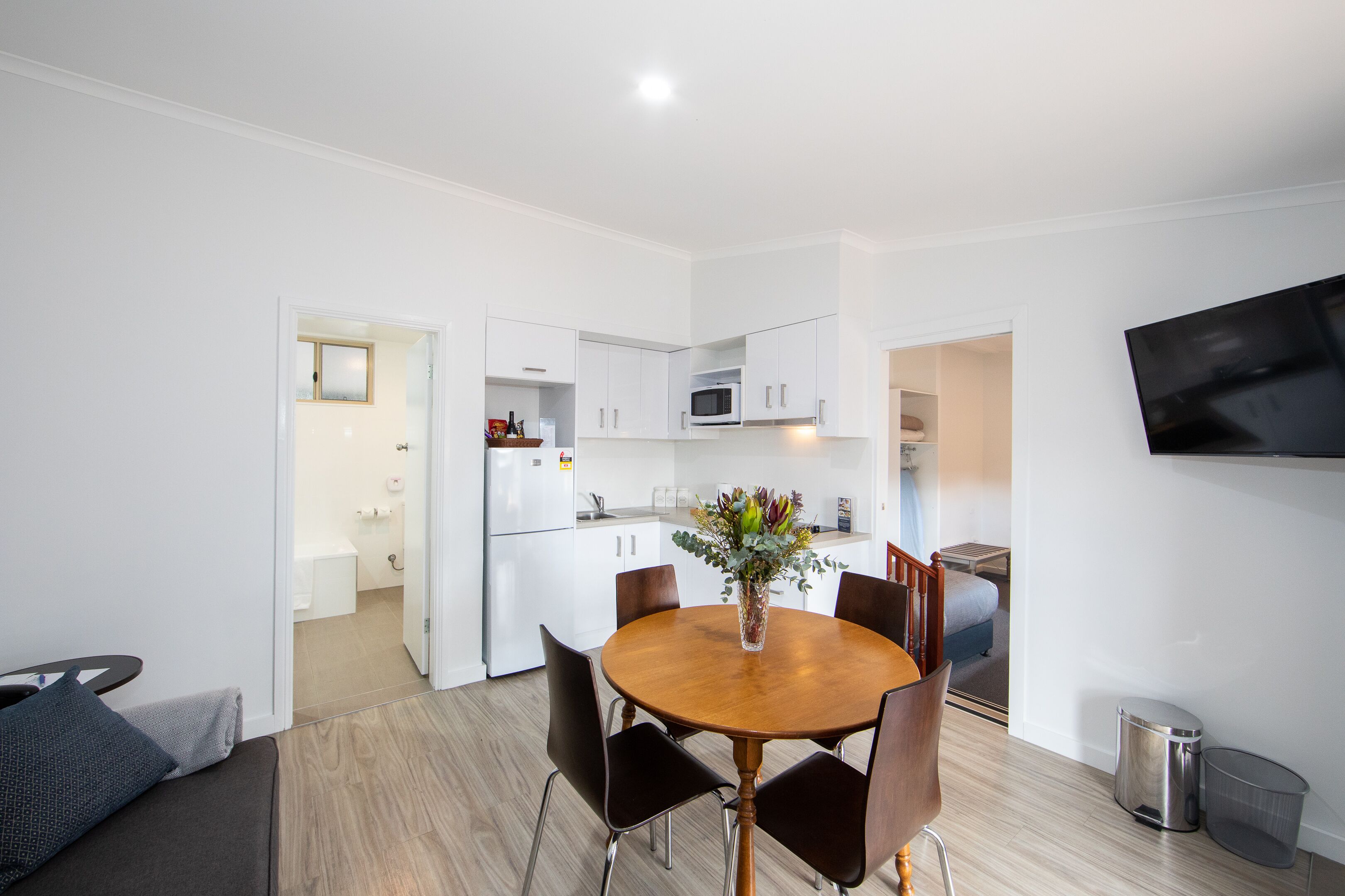 A modern kitchen with white cabinets, a microwave, and a dining area with a wooden table and chairs.