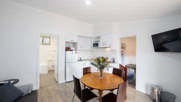 A modern kitchen with white cabinets, a microwave, and a dining area with a wooden table and chairs.