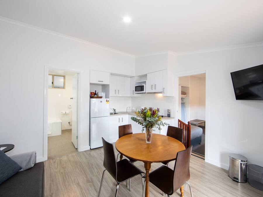 A modern kitchen with white cabinets, a microwave, and a dining area with a wooden table and chairs.