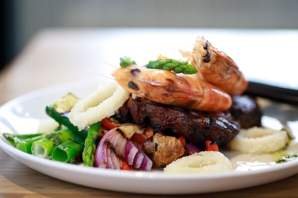 A plate of food with grilled shrimp, steak, asparagus, and potatoes.