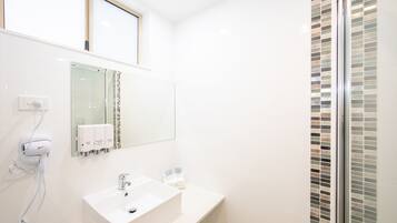 A modern bathroom with a white sink, a mirror, and a glass shower enclosure.