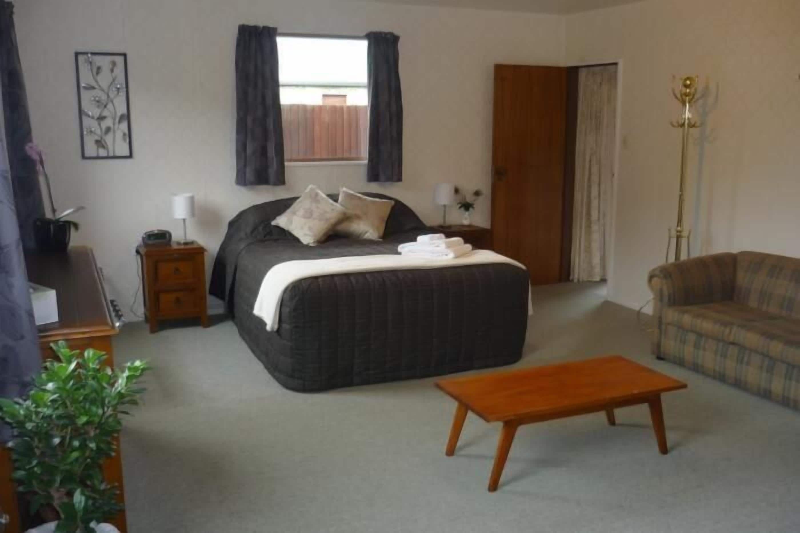 A bedroom with a bed, bedside table, lamp, and a chair.