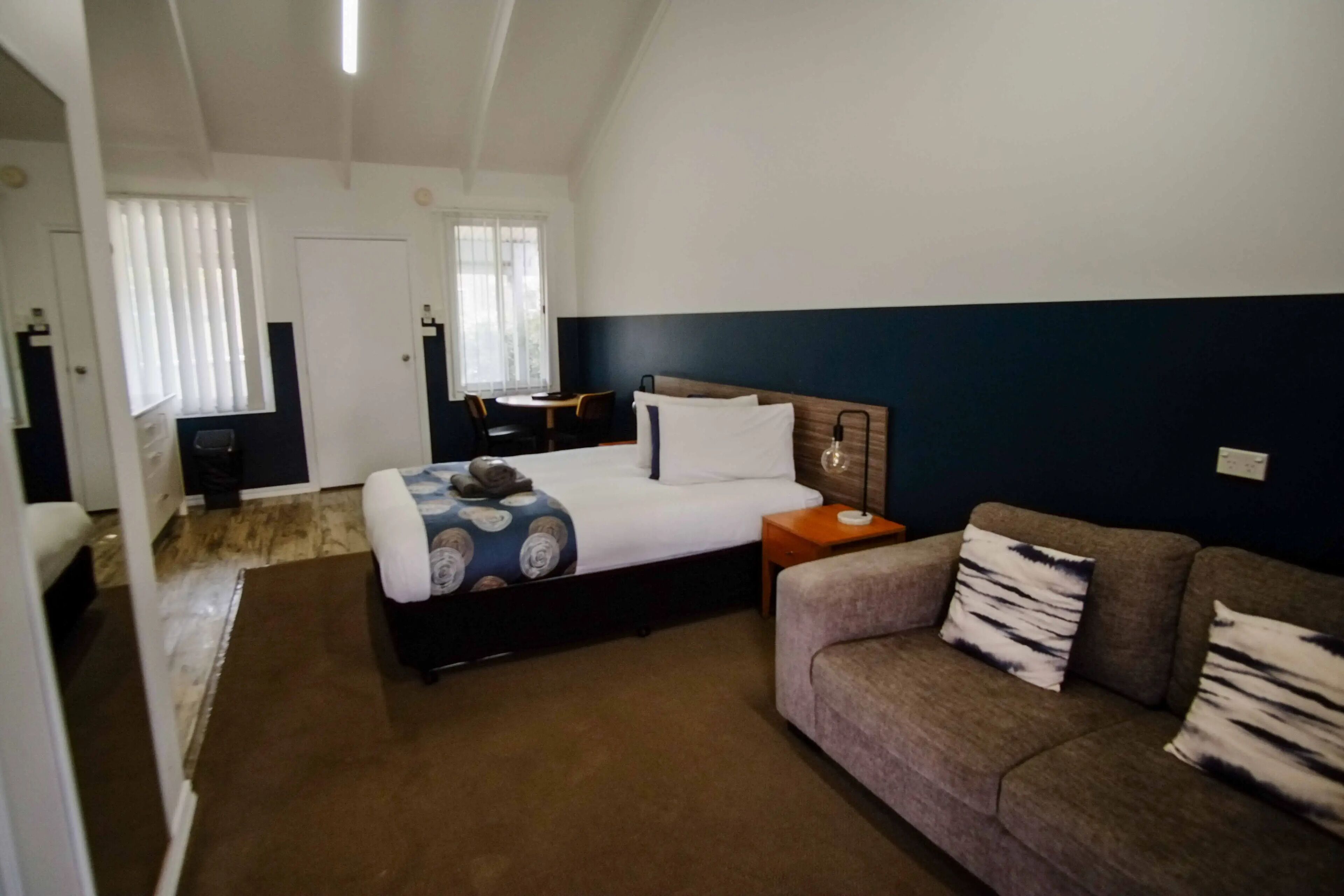 Una habitación de hotel con cama, sofá, escritorio y ventana con persianas.