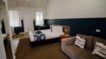 Una habitación de hotel con cama, sofá, escritorio y ventana con persianas.