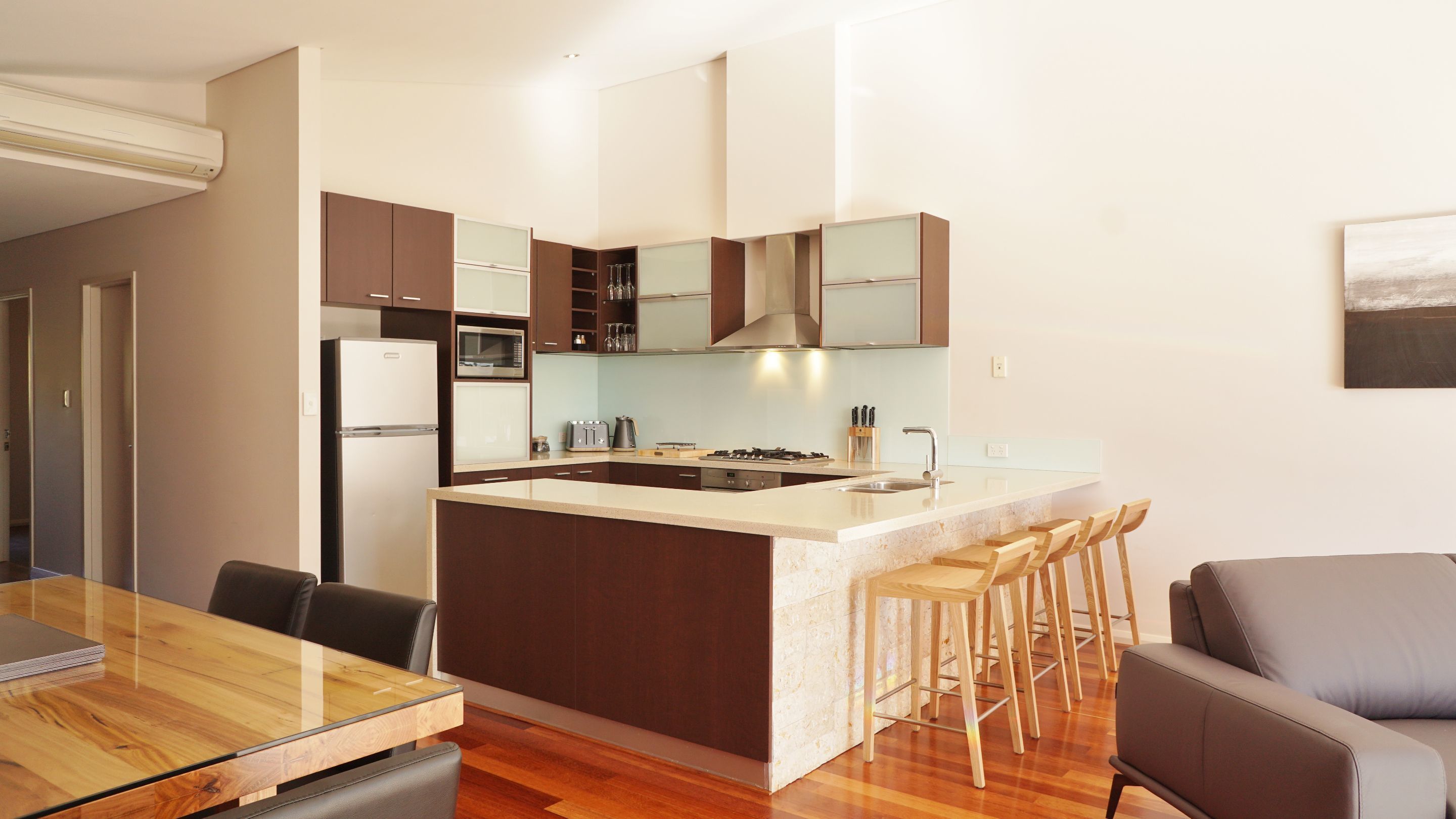 Una cocina moderna con una isla central, sillas de madera y una mesa de comedor.