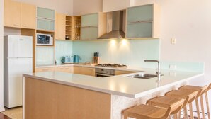 Una cocina moderna con una isla central, taburetes de bar, microondas y estufa a gas.